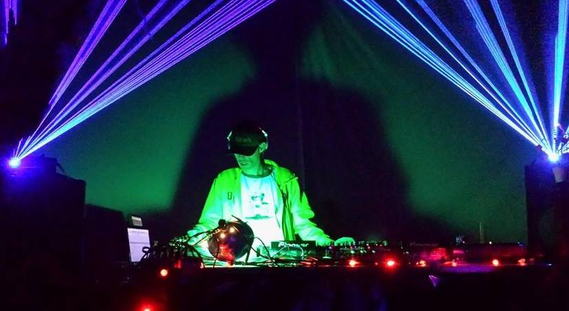 DJ Natural Nate® under dramatic laser beams and green stage lighting